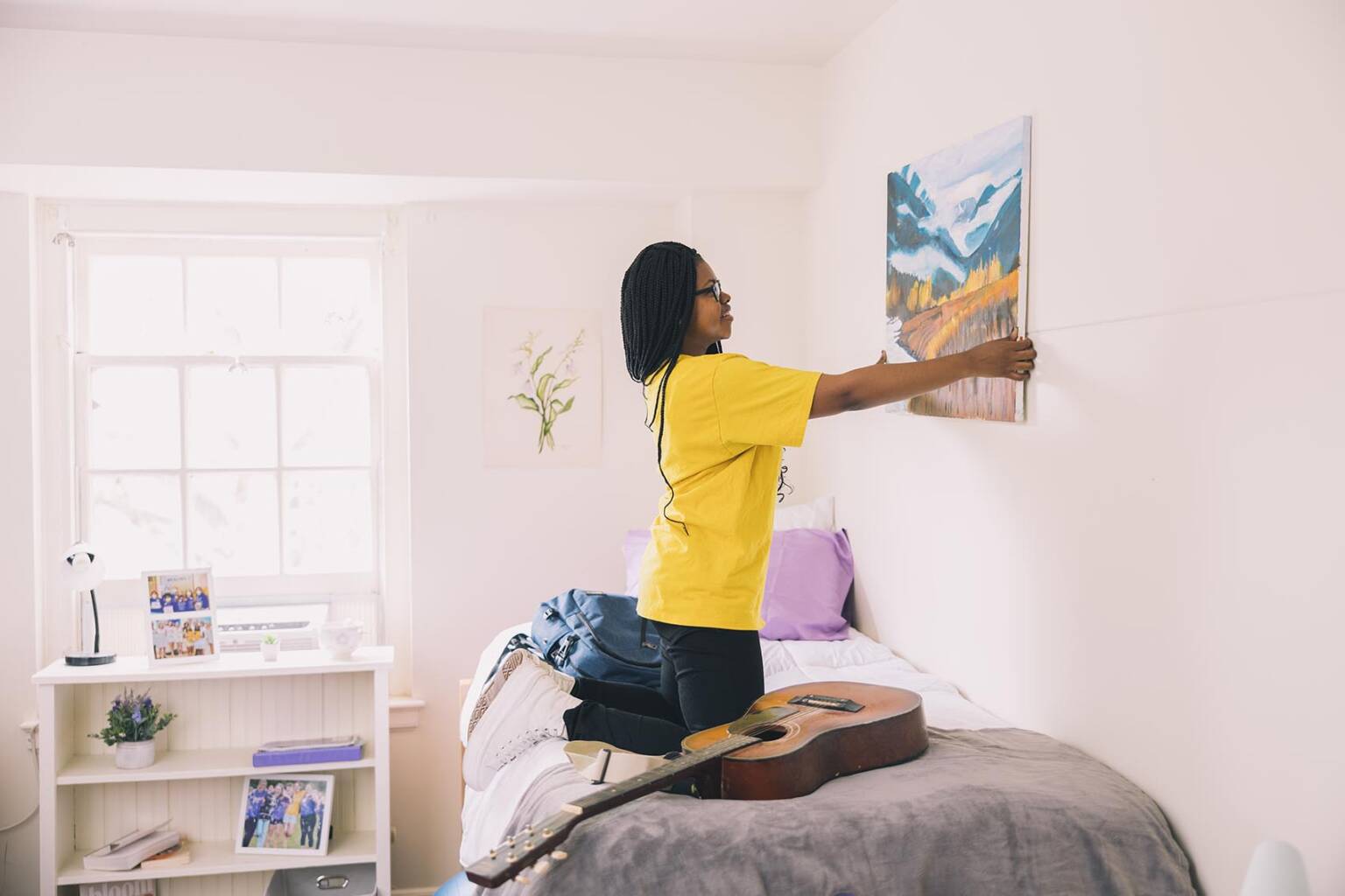 student hanging up poster in her room